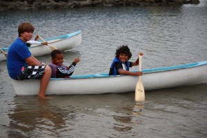Three boys smiling in a canoe